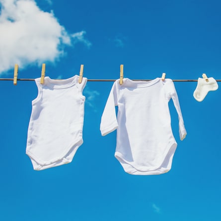Weisse Babykleidung trocknet an der Sonne draussen. Weisse Babykleidung trocknet an der Sonne draussen.
